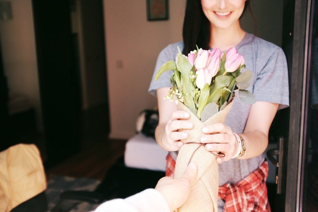 A lady being handed a bouquet of tulips in brown paper wrapping for a post about the ways to buy flowers more ethically.