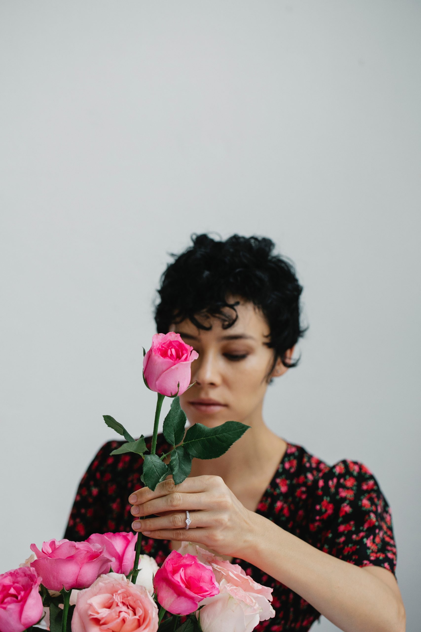 A woman arranges pink rose in a vase. Post includes tips for keeping a bouquet fresher for longer. Photo by Michelle Leman from Pexels